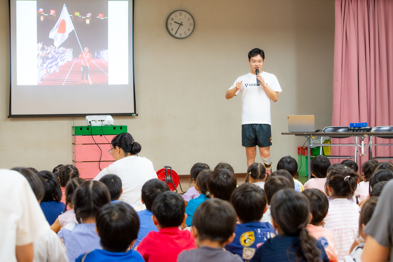 岩渕幸洋選手が立って話していて、子どもたちは座って聞いている