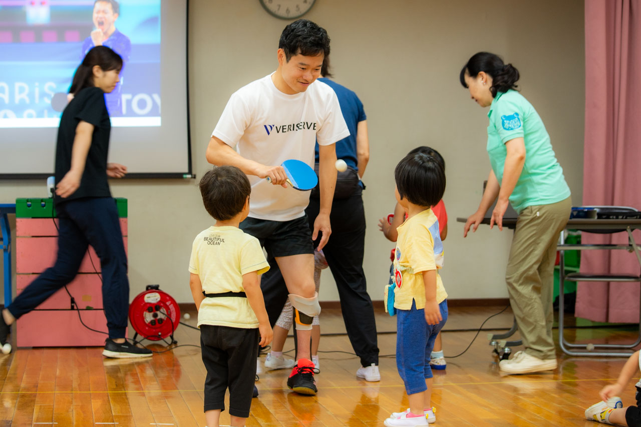 子どもたちに囲まれた岩渕幸洋選手が、みんなに卓球を教えている