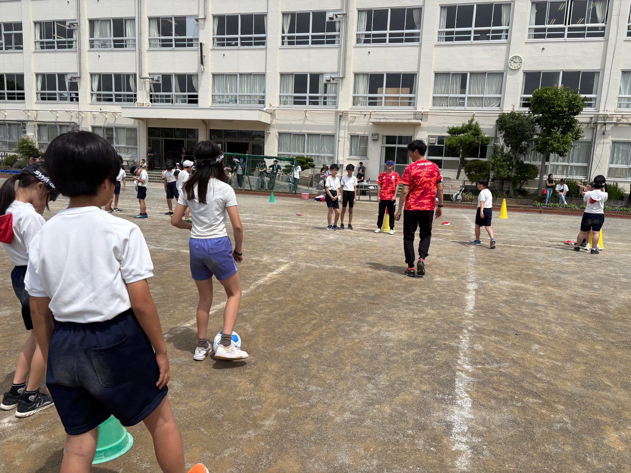 アイシェードを装着した園部選手とパス交換する児童を見守る上林氏