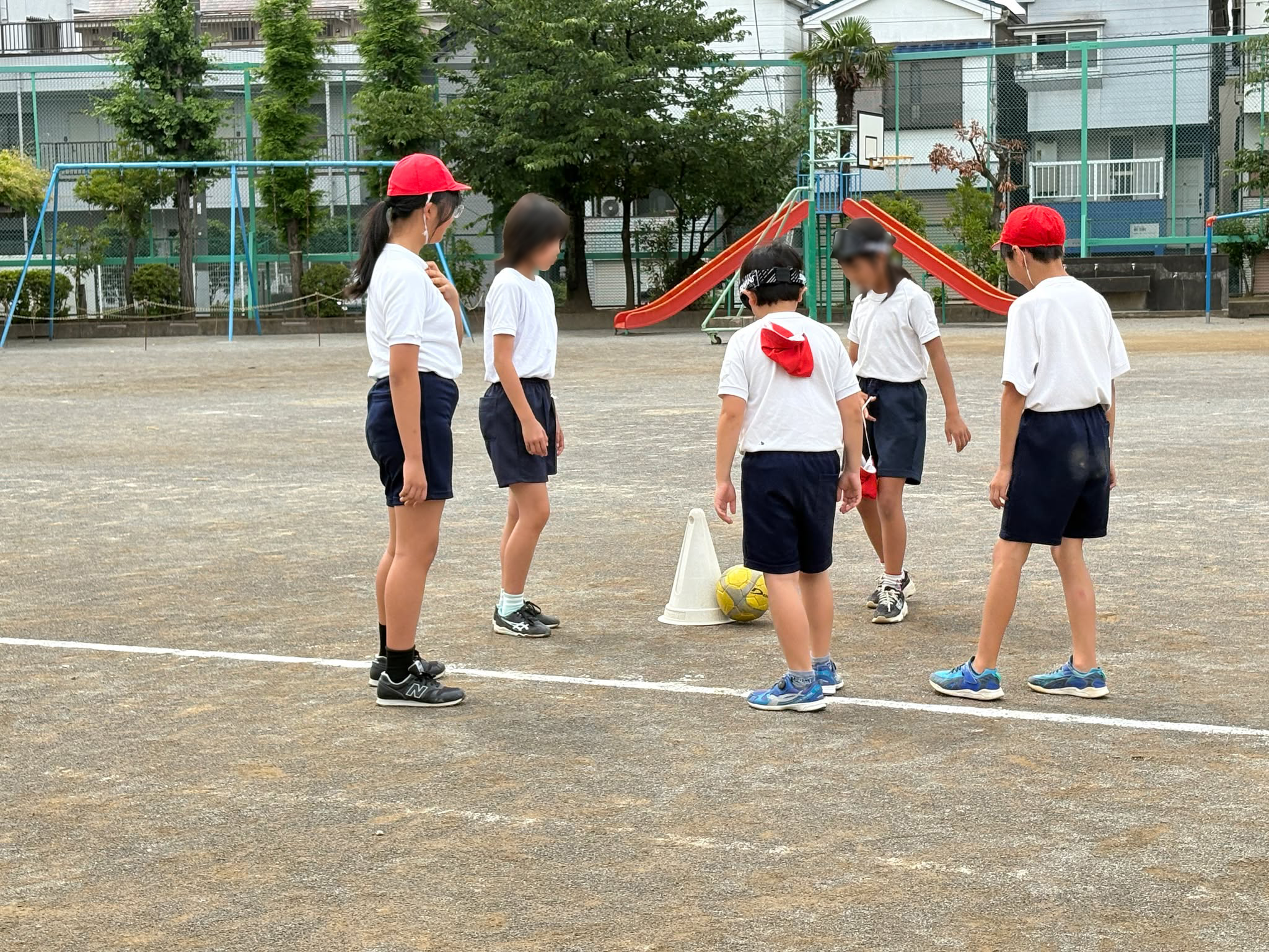 アイシェードを装着してドリブルする児童を声でサポートする周りの児童