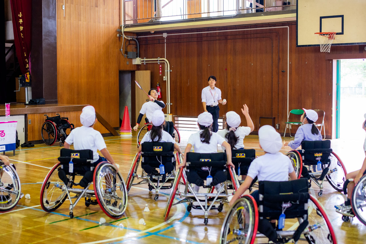 競技用車いすに乗った長島選手がラケットでシャトルを打つ width=